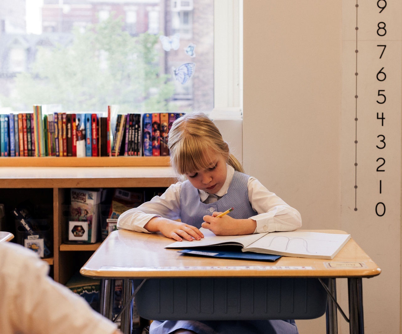 An attentive girl in a lower school environment, sitting at a desk and engaged in her academic tasks