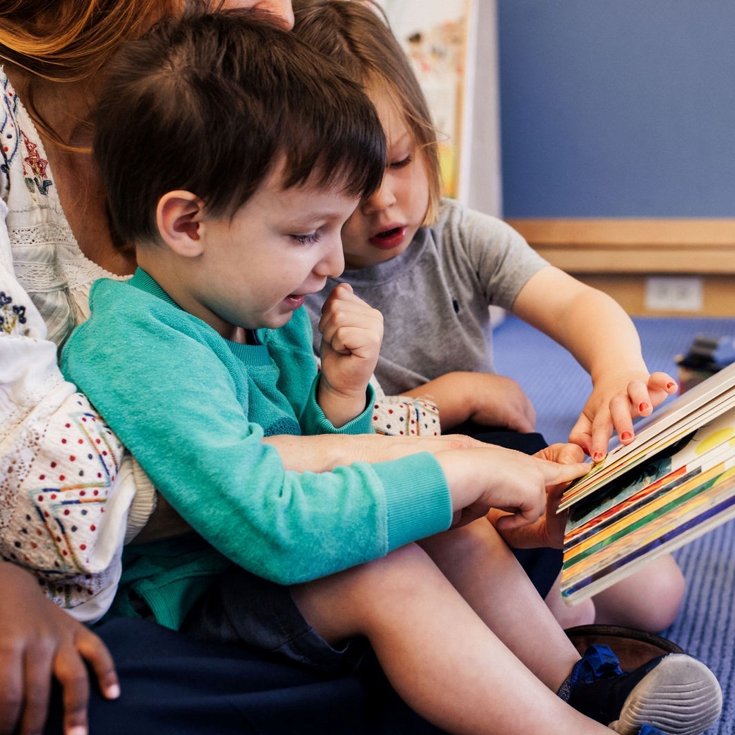A woman and two children captivated by a book, enjoying a special moment of reading together in an early childhood program