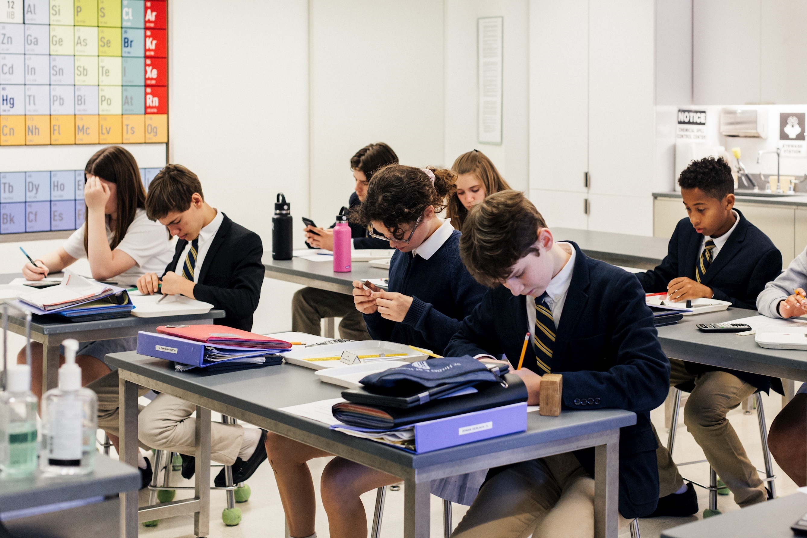 Upper school students focused on their homework, collaborating and studying together in a classroom.
